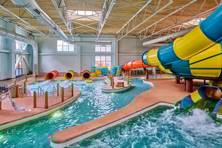 A father and son going down the Coyote Cannon water slide together on a yellow raft.