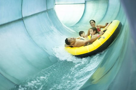 Family of four rides down waterslide in yellow tube