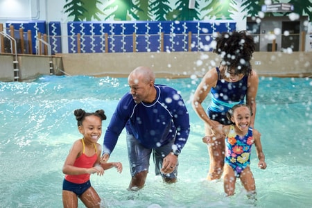 Family of four splashing water in a wave pool
