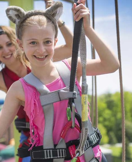 Girl in harness climbing on the Howlers Peak Ropes Course