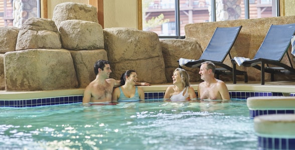 Two couples relax in an indoor hot tub