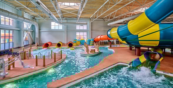 A father and son going down the Coyote Cannon water slide together on a yellow raft.