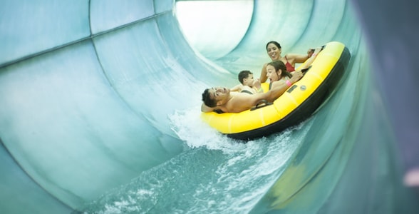 Family of four rides down waterslide in yellow tube