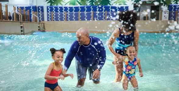Family of four splashing water in a wave pool