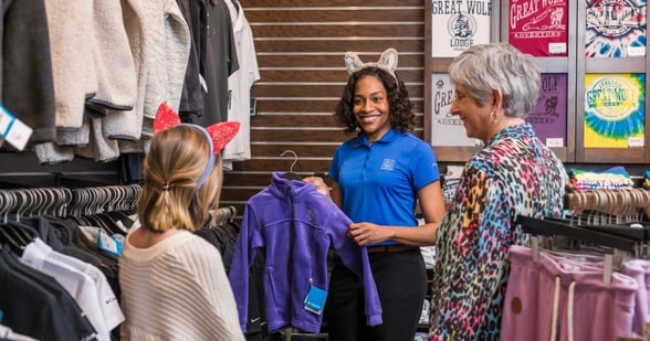 Employee showing customers souvenir options