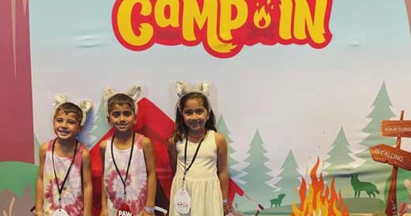 kids taking a pause in front of the Summer Camp In banner