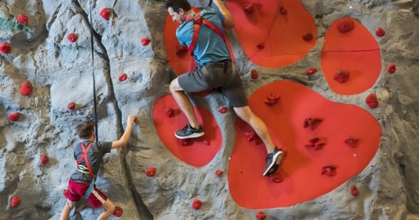 father and son climbing an indoor wall