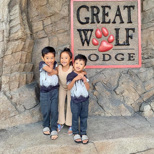 three kids taking a pause in front of the great wolf lodge sign