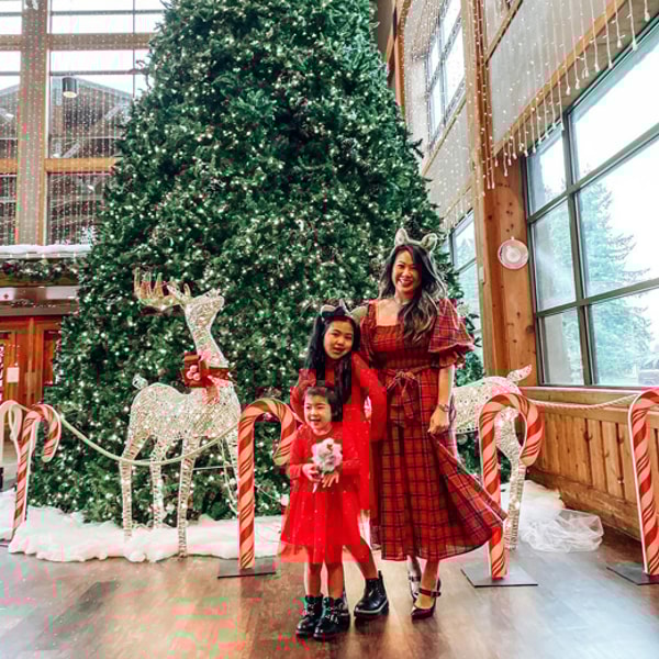 mother and her two daughters in front of a Christmas tree