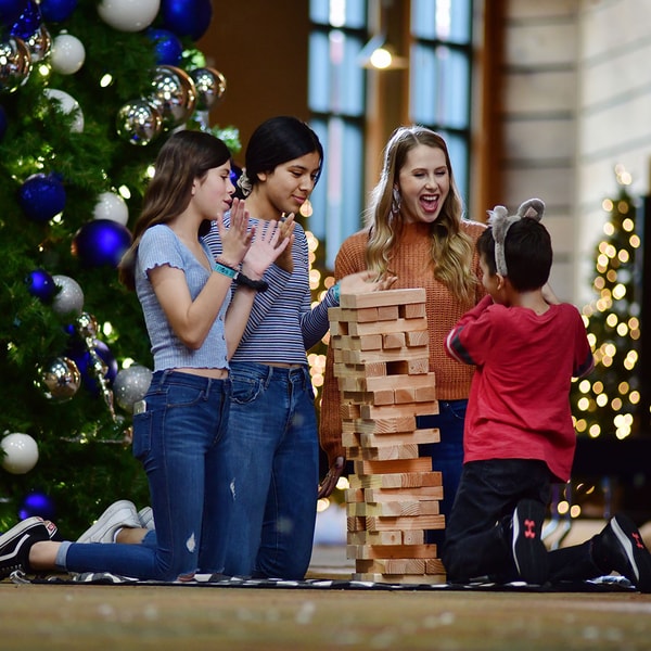 family playing jenga next to a holiday tree