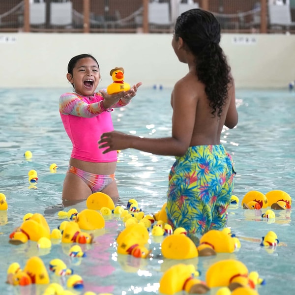 mother and daughter playing with duck in the pool