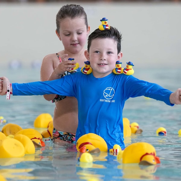 son and father enjoying with rubber ducks in the pool