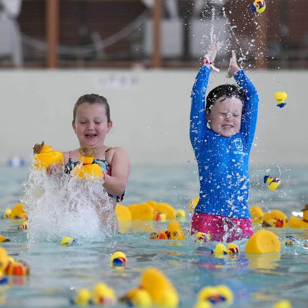 son enjoys with toy ducks as father watches happily