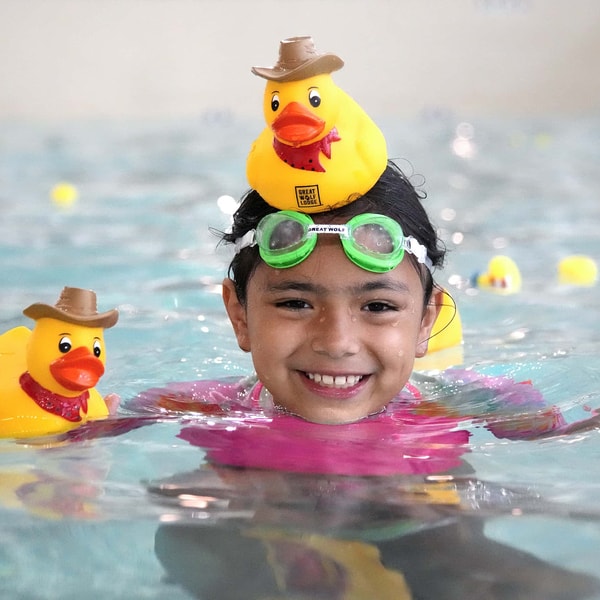 boy has a rubber deck sitting on his head as he laughs