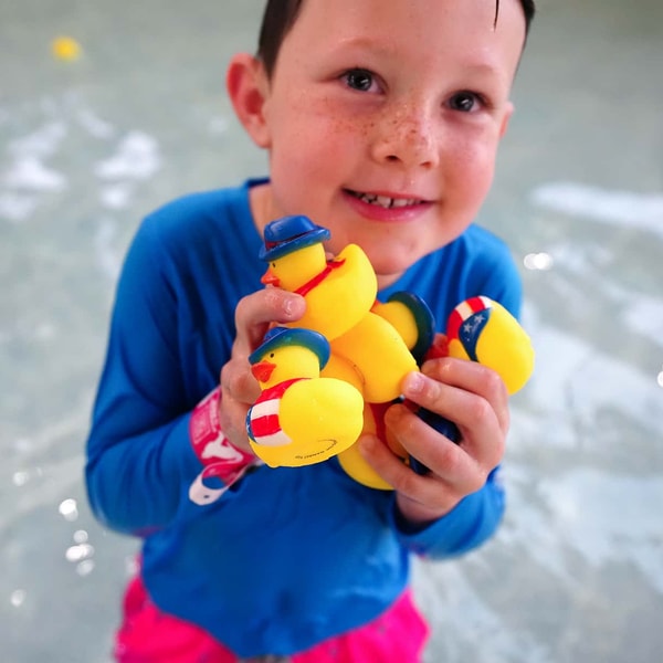 boy holding ducks in a pool