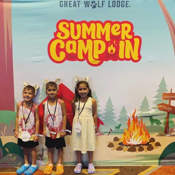 three kids posing in front of the summer camp in mural