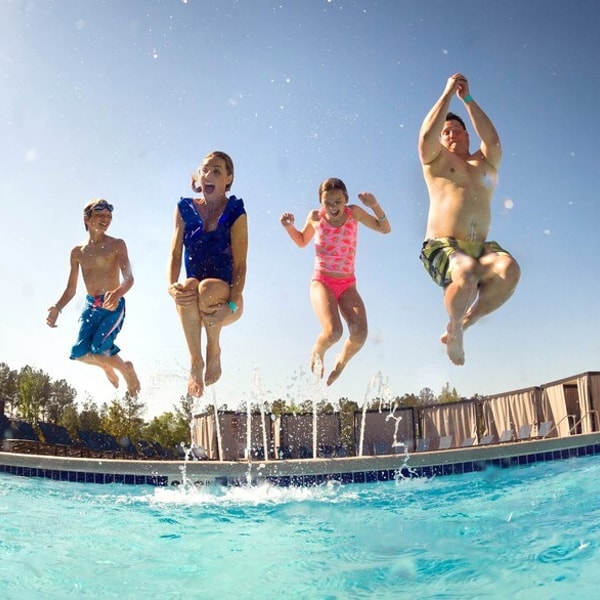 a family of four jumping in a pool