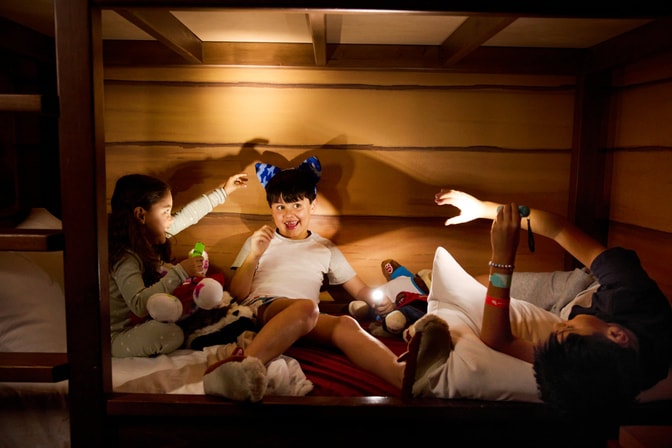 Kids playing with flashlights on bunk bed in themed Den guest room