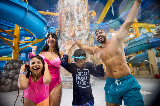family standing under the water bucket splashing water