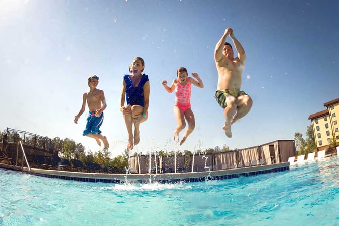 Family jumping into an outdoor pool at Great Wolf Lodge