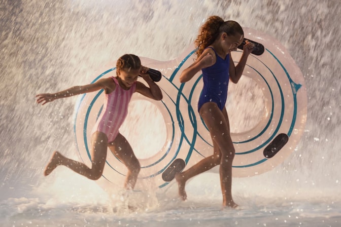 girls holding floating tubes getting soaked in water