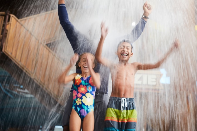 kids and father standing under a water bucket and getting splashed