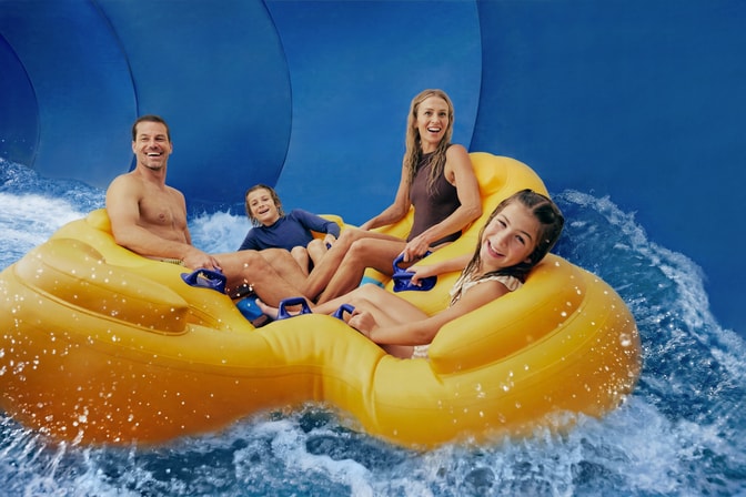 Family enjoying water park slide on yellow floats.