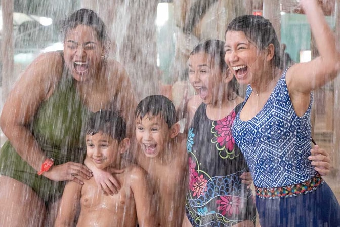 kids and mothers standing under a water bucket and getting splashed
