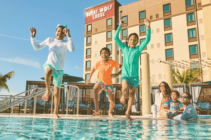 three children jumping into a pool making a splash