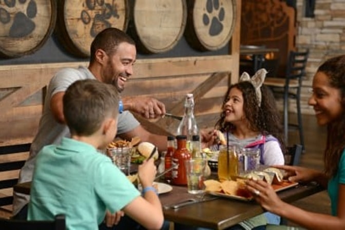 A family of three enjoy dinner at a Great Wolf Lodge indoor water park and resort restaurant.