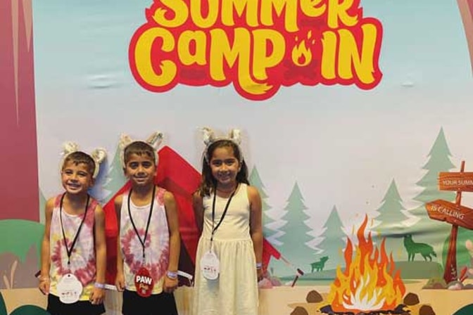 kids taking a pause in front of the Summer Camp In banner