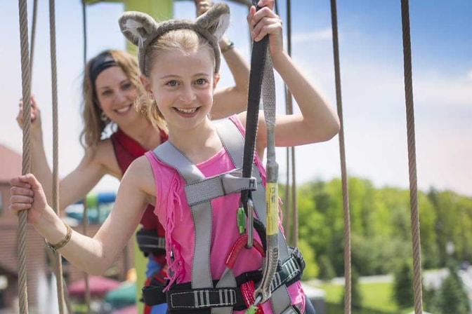 Girl in harness climbing on the Howlers Peak Ropes Course