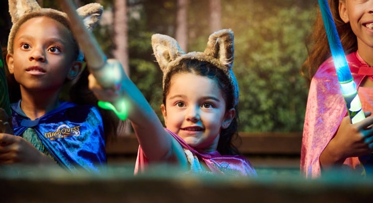 little girl placing a cape on little girl at MagiQuest interactive game