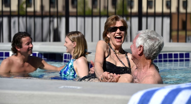 A couple relax in and on the side of the indoor pool 