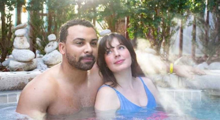 A couple relax by the outdoor whirlpool spa at Great Wolf Lodge indoor water park and resort.