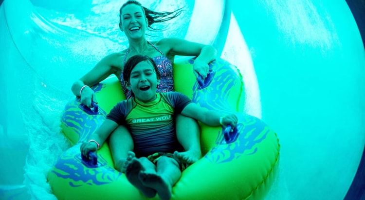 Mother and son in a tube racing down a yellow waterslide 