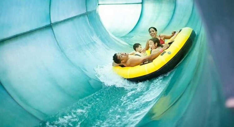 Family of four rides down waterslide in yellow tube