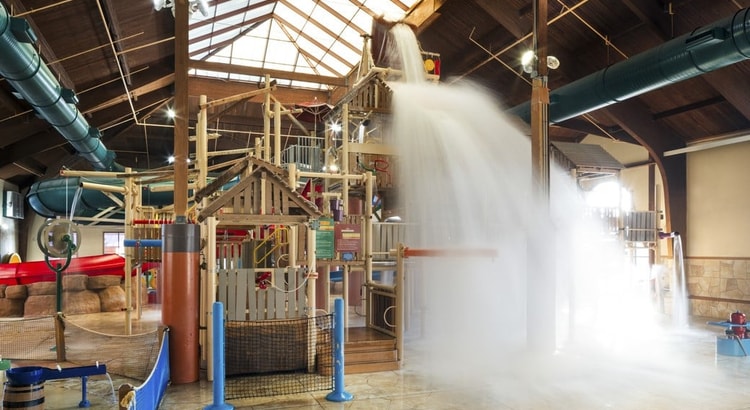 A wide shot of the  water treehouse as water splashes down from a bucket above the jungle gym