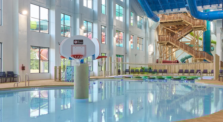 family playing basketball in indoor pool 