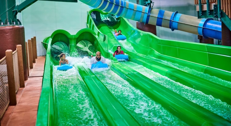 Guests race down a waterslide laying on their stomaches 