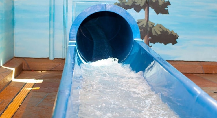 The end of a blue waterslide with water splashing out