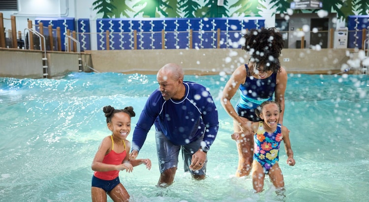 Family of four splashing water in a wave pool