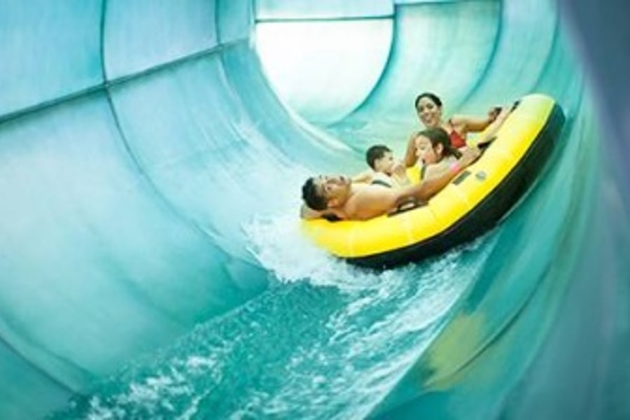 Family of four rides down waterslide in yellow tube