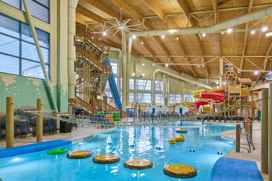 A girl balances on a lily pad float in indoor pool