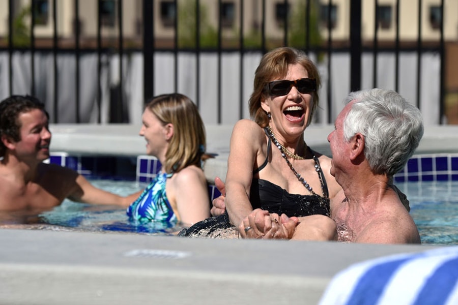 A couple relax in and on the side of the indoor pool 