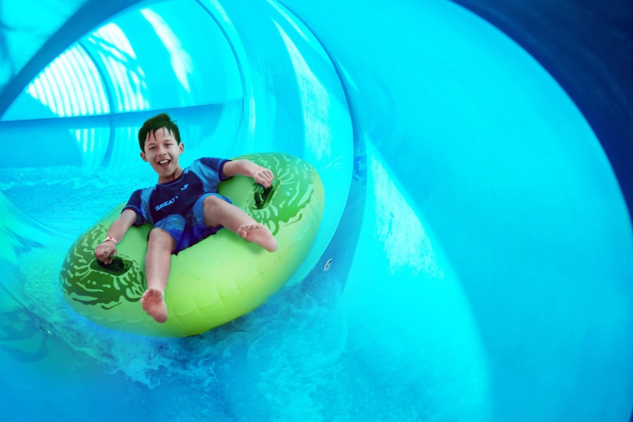 Boy rides down blue waterslide on yellow tube