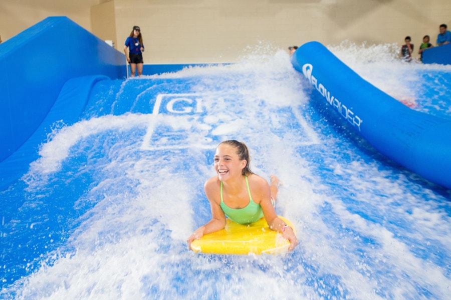 A child rides on a yellow boogie board in the water attraction 