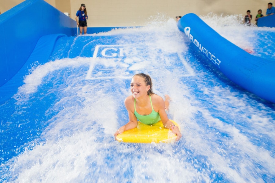 A child rides on a yellow boogie board in the water attraction