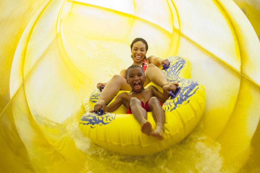 Mother and son in a tube racing down a yellow waterslide