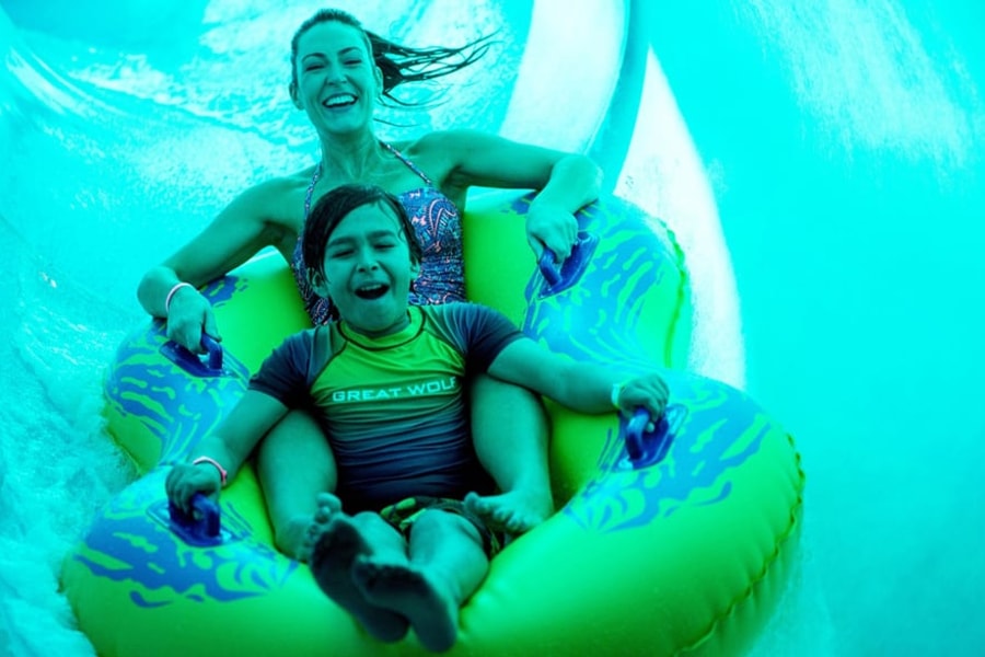 Mother and son in a tube racing down a yellow waterslide 